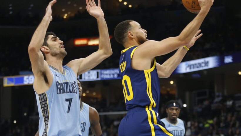Golden State Warriors guard Stephen Curry goes a reverse layup while Memphis Grizzlies forward Santi Aldama defends