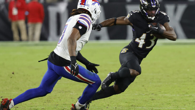 Baltimore Ravens running back Justice Hill runs with the ball as Buffalo Bills safety Damar Hamlin runs towards him