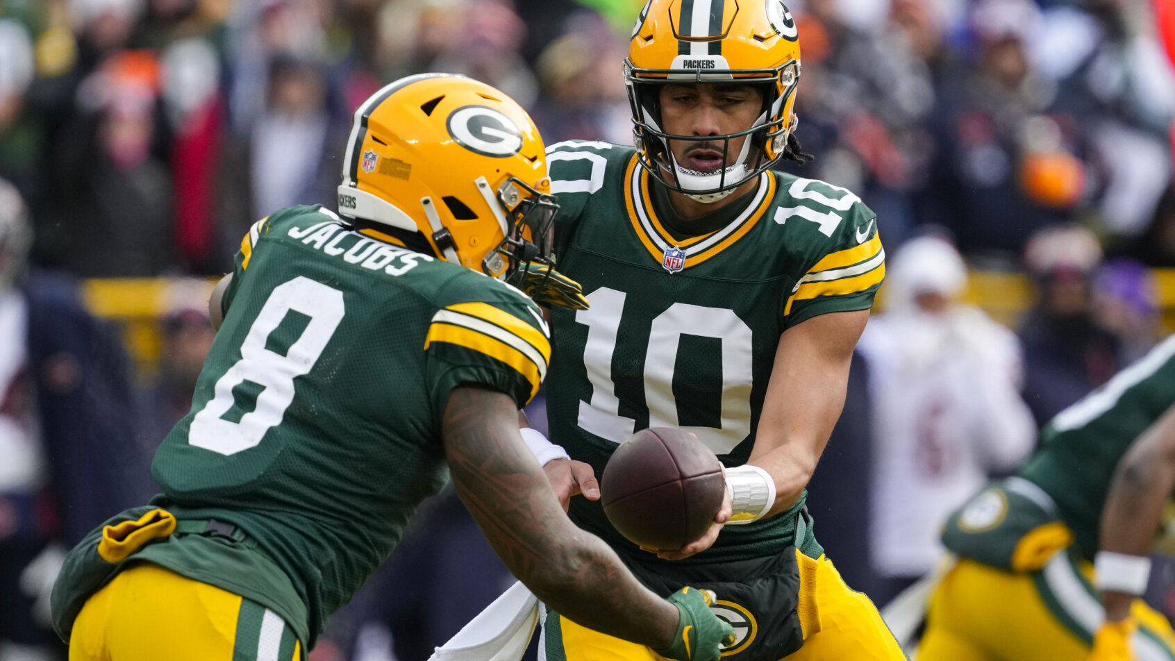 Green Bay Packers quarterback Jordan Love hands the football off to running back Josh Jacobs
