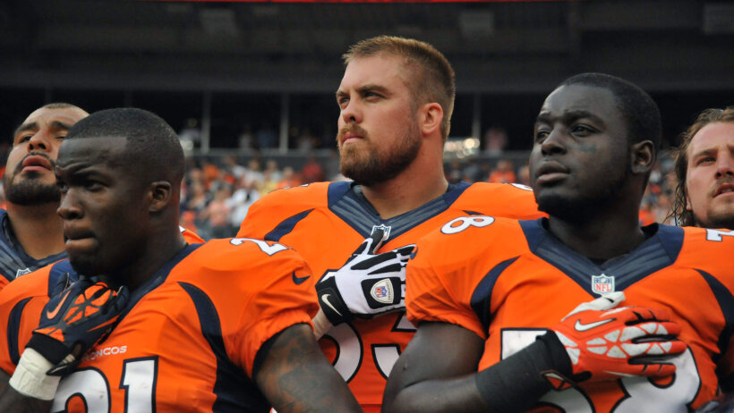 Three Denver Broncos standing for the National Anthem
