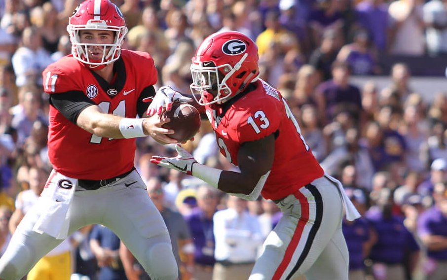 Georgia Bulldogs quarterback Jake Fromm hands the ball off to running back Elijah Holyfield