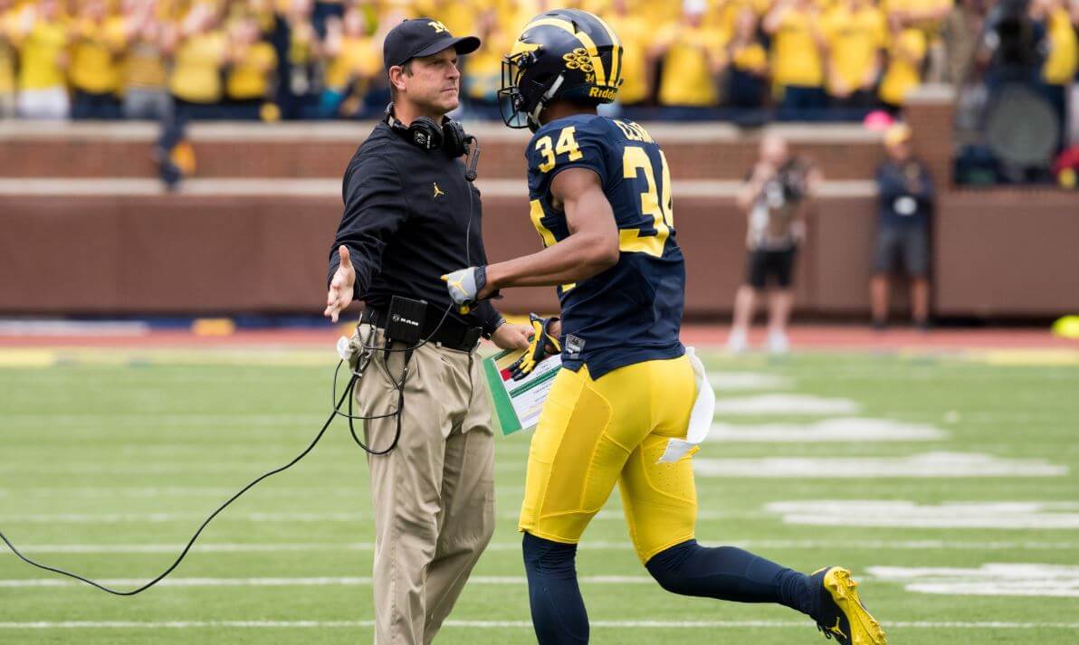 Jim Harbaugh high fiving one of his Michigan players.