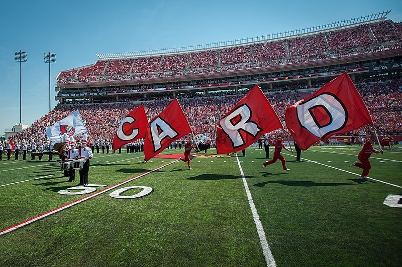 Louisville Cardinals cheerleaders running across the field.
