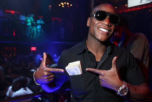 Floyd Mayweather pointing at a wad of money in his pocket.