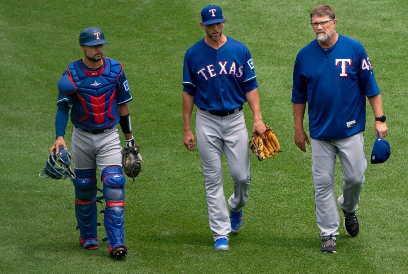 Mike Minor walking to the mound with Ranger teammates and coaches.