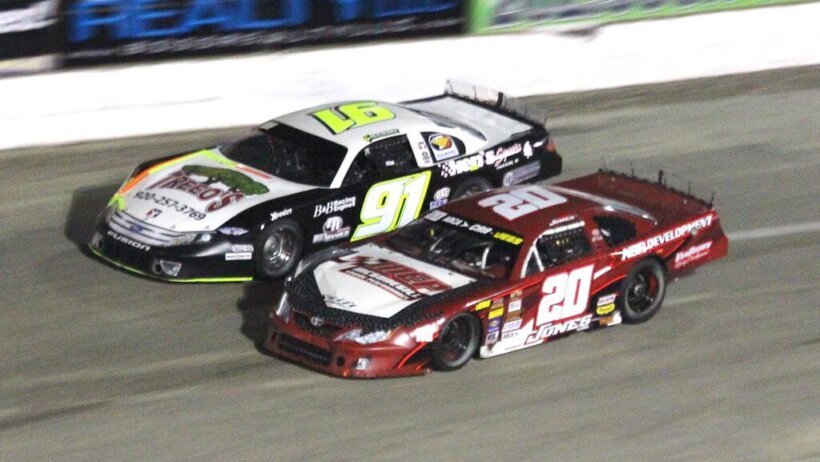 NASCAR drivers neck and neck on the wall.
