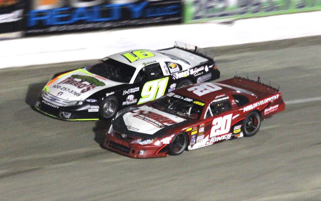 NASCAR drivers neck and neck on the wall.