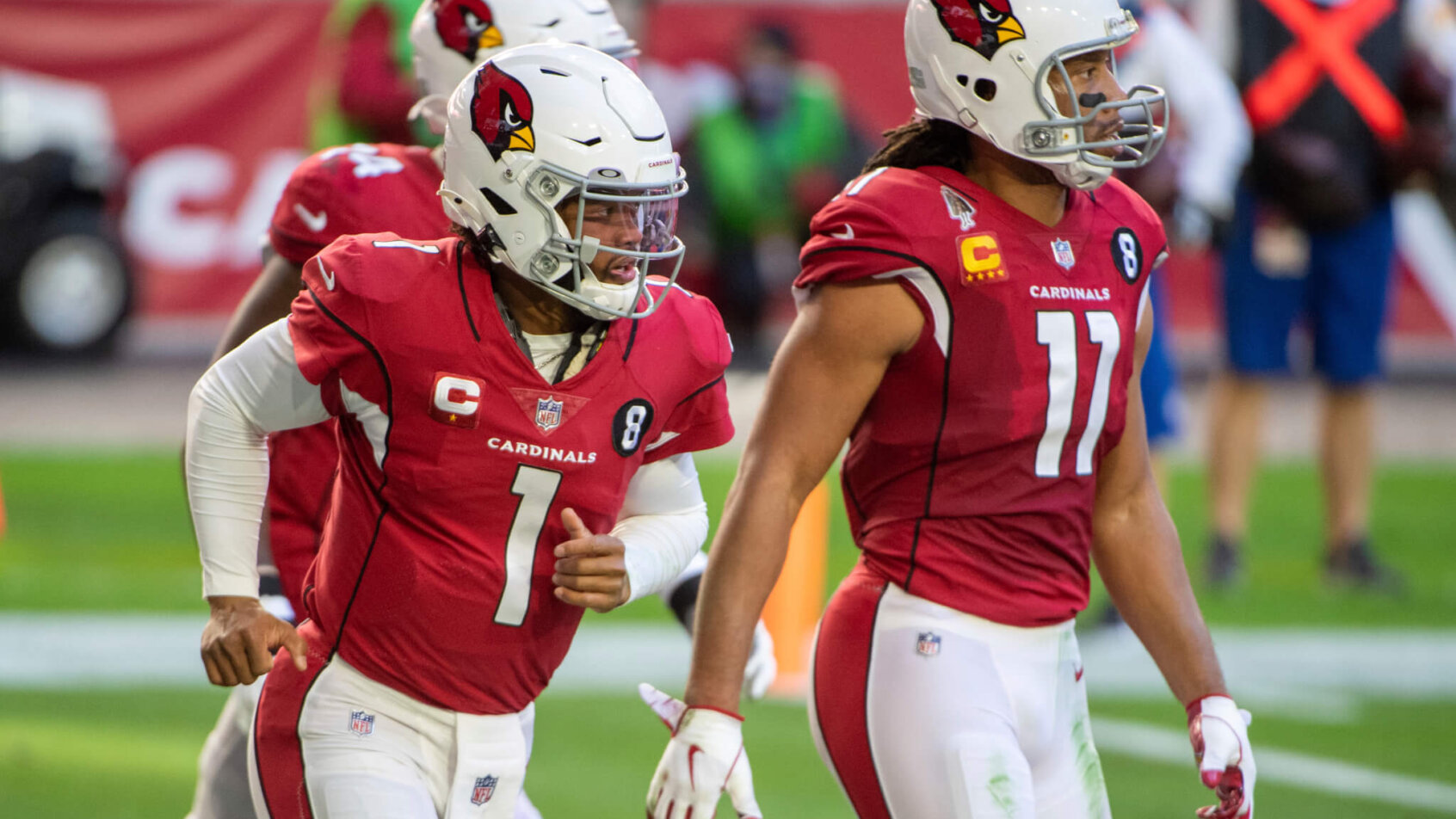 Arizona Cardinals quarterback Kyler Murray, and wide receiver Larry Fitzgerald walking on the football field.