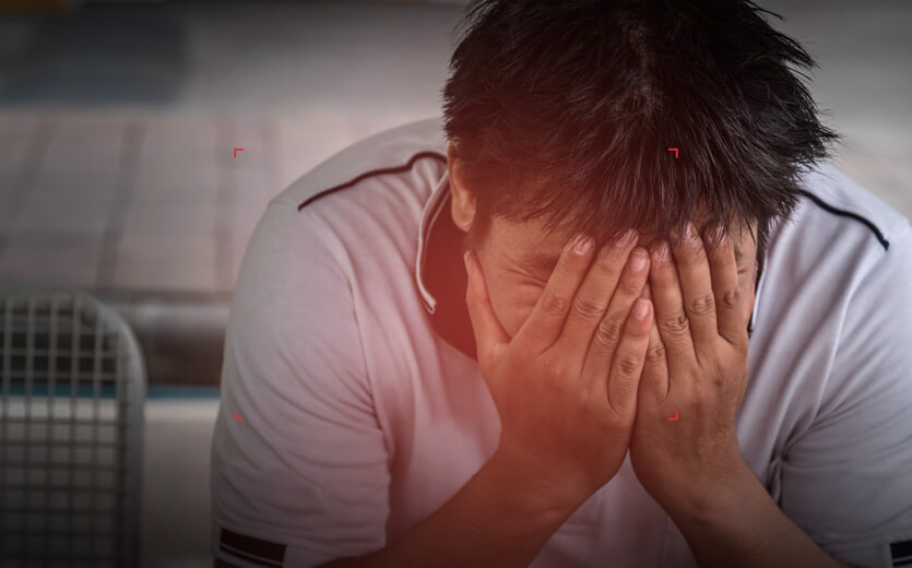 image of a man holding his face in his hands in distress