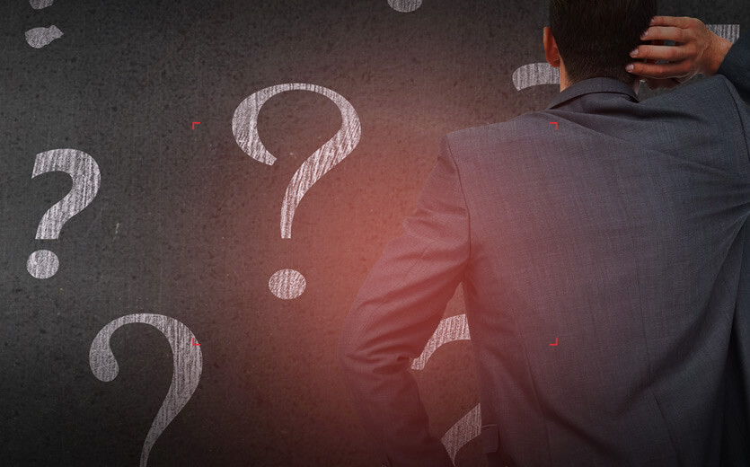 image of a man standing in front of a wall covered with question marks