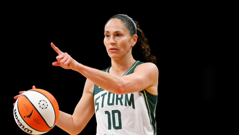 Sue Bird dribbling with right hand, pointing with left hand