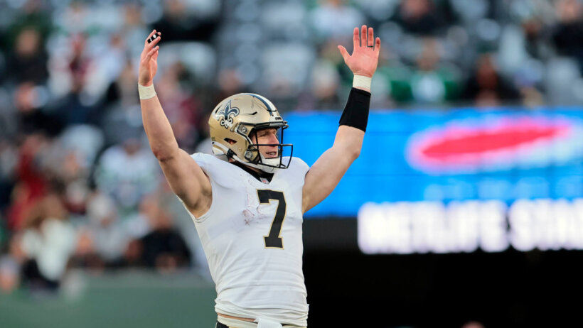 New Orleans Saints quarterback Taysom Hill reacting with his hands in the air on the field during a game.