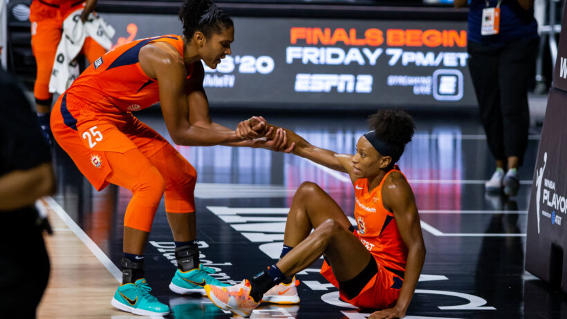 Connecticut Sun player orange jersey helping up other player