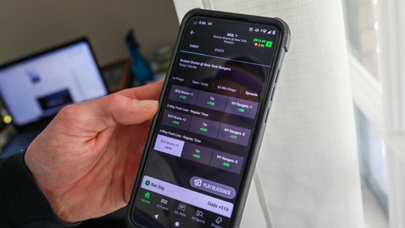 DraftKings user holding mobile phone with app open