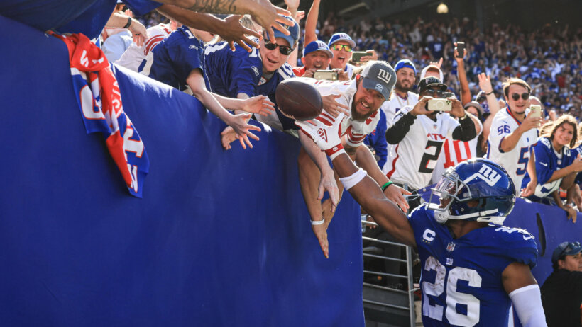 New York Giants Saquon Barkley throws football to fans