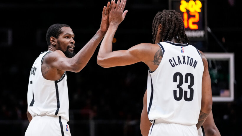 Kevin Durant and Nic Claxton high fiving during a game.
