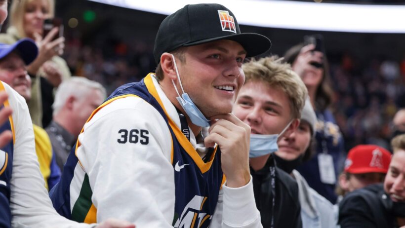 New York Jets quarterback Zach Wilson sits on court side watching the game between the Utah Jazz and the Golden State Warriors