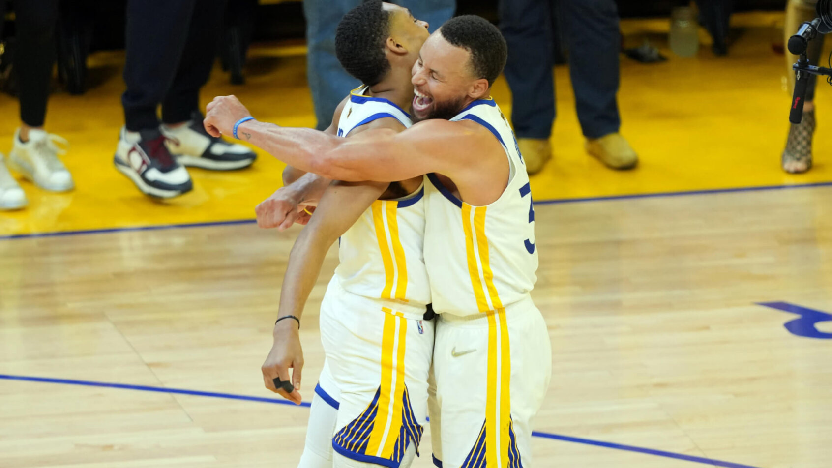 Golden State Warriors teammates Jordan Poole and Steph Curry hugging after a win