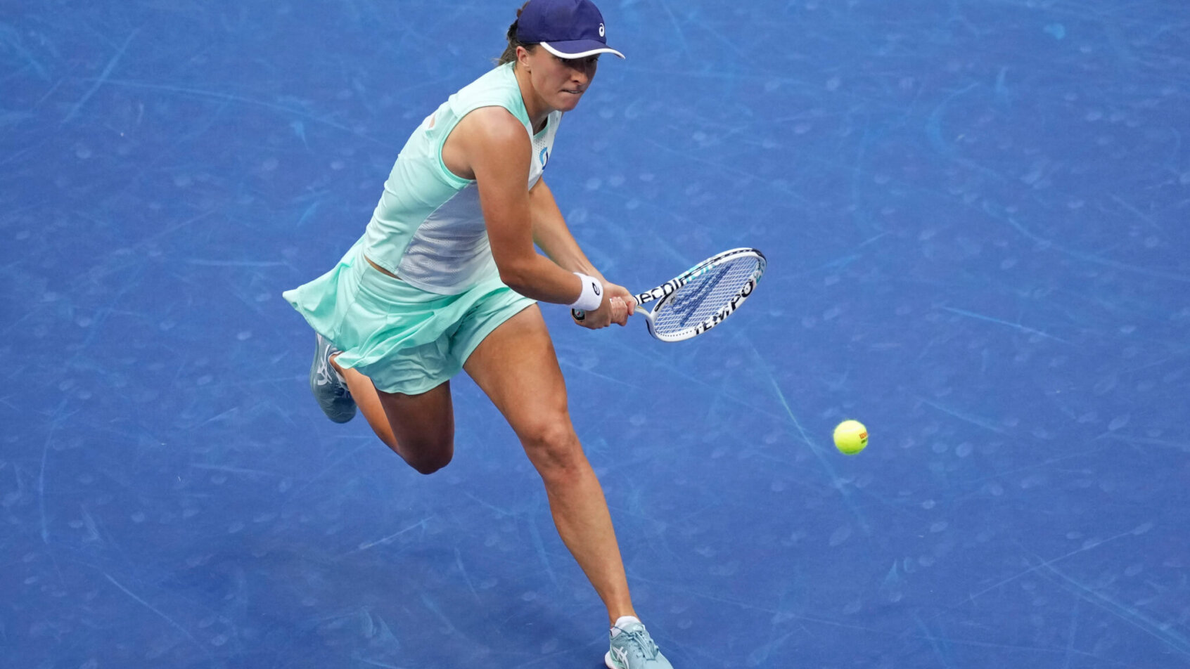 Iga Swiatek hitting a backhand during a tennis match.