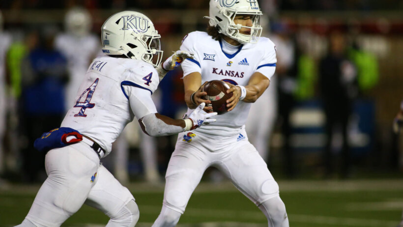 Kansas Jayhawks quarterback Jason Bean hands the ball to running back Devin Neal