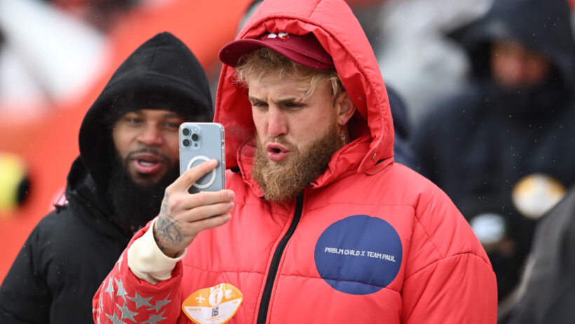 Jake Paul red coat holding mobile phone