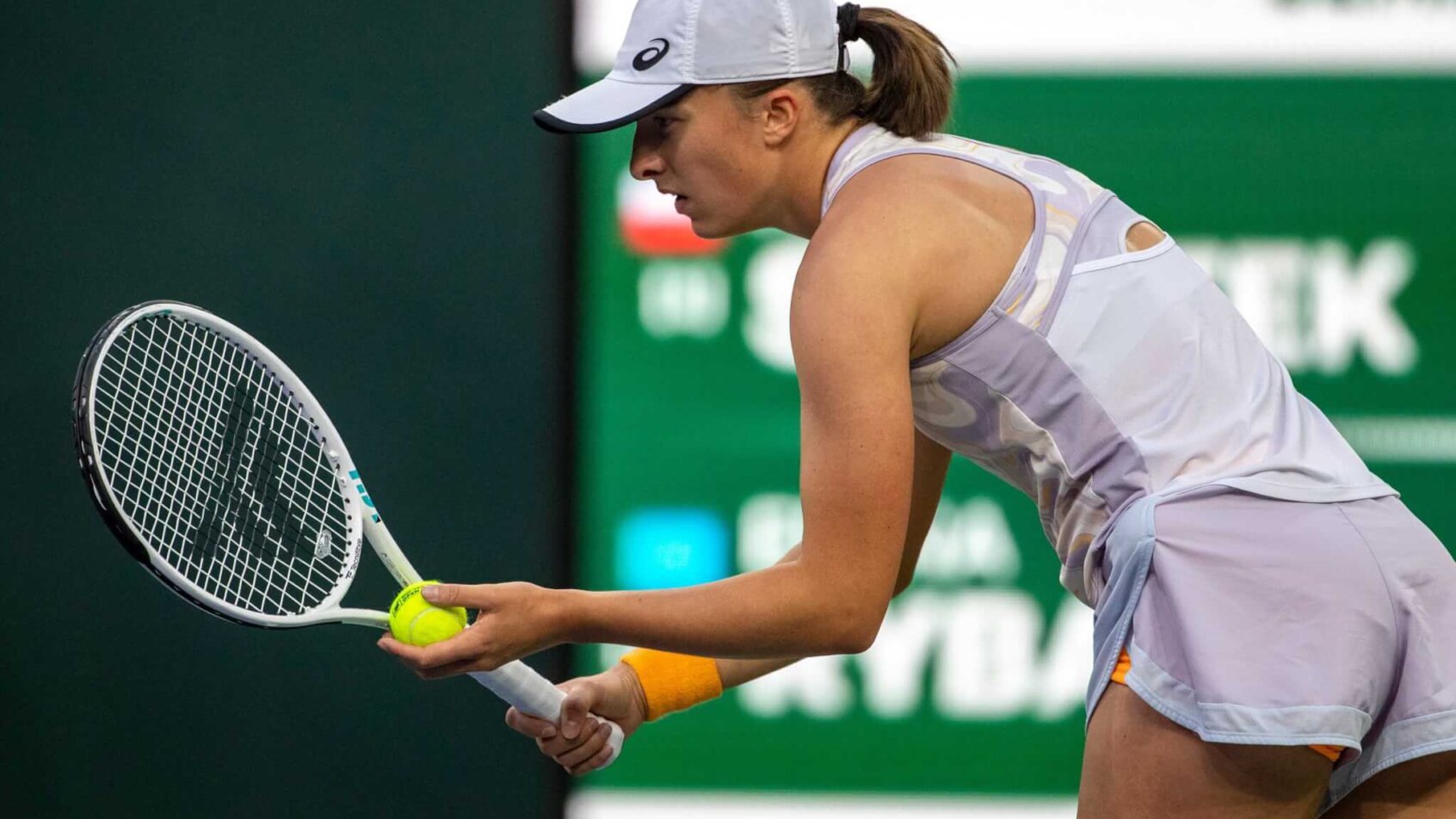 Iga Swiatek preparing a serve during a tennis match.