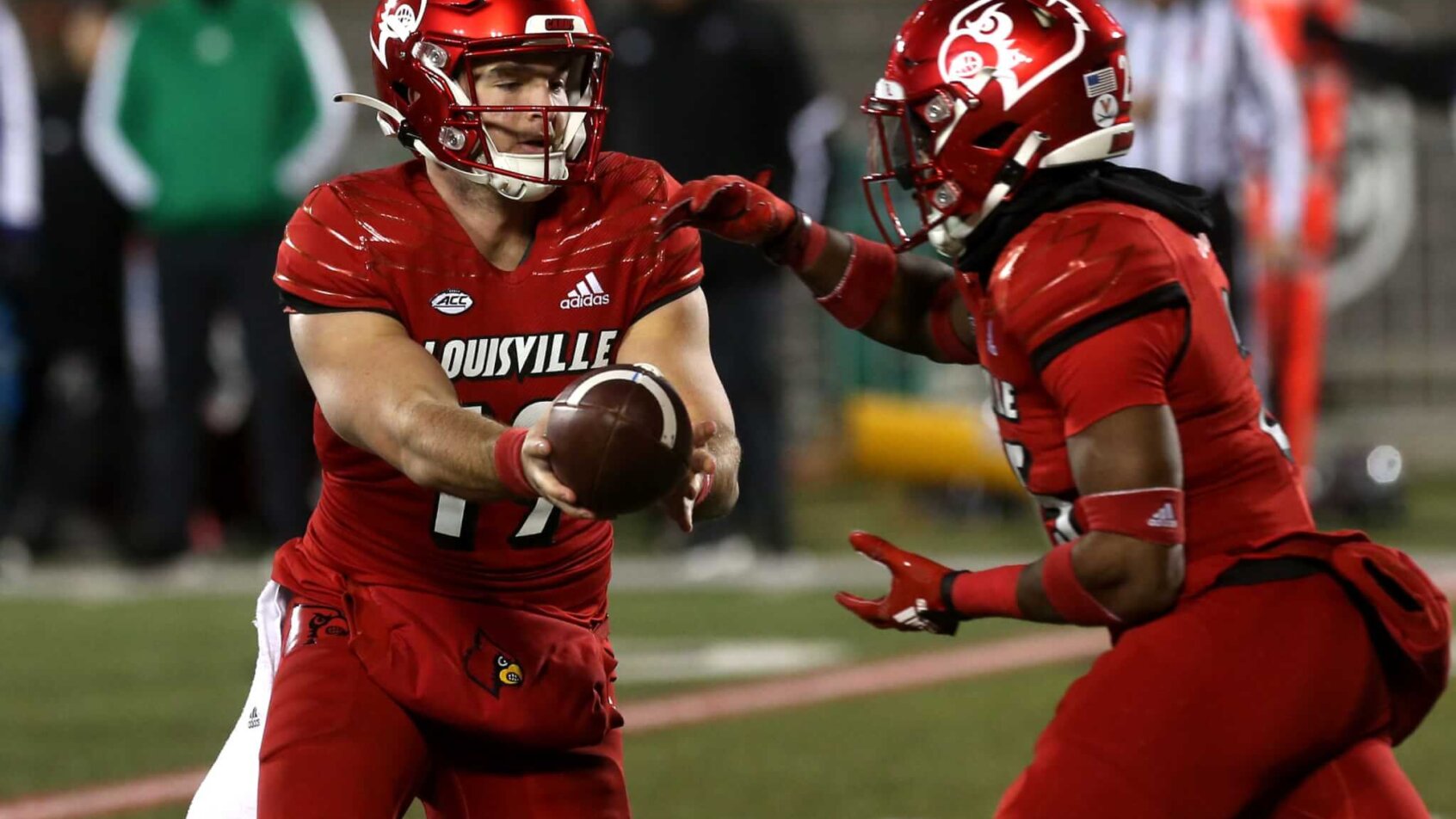 Louisville’s Brock Domann hands the ball off to Jawhar Jordan