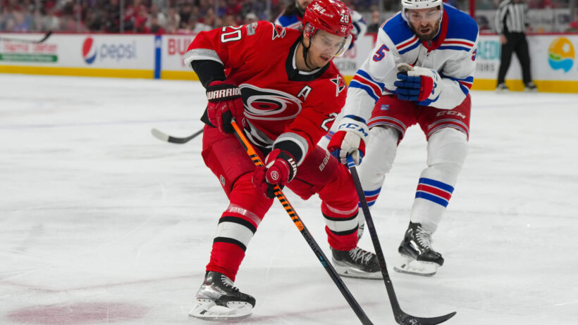 Carolina Hurricanes center Sebastian Aho skates with puck past New York Rangers defenseman Ben Harpur