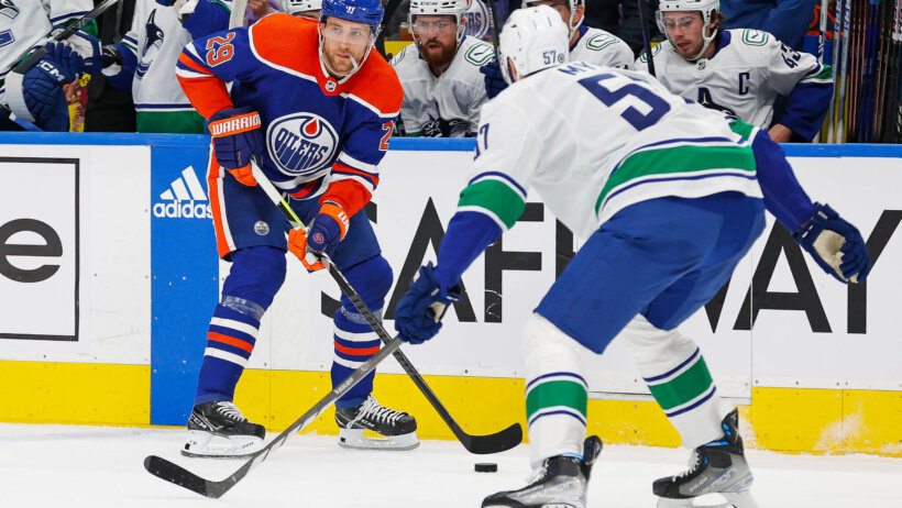 Edmonton Oilers forward Leon Draisaitl looks to make a pass in front of Vancouver Canucks defensemen Tyler Myers
