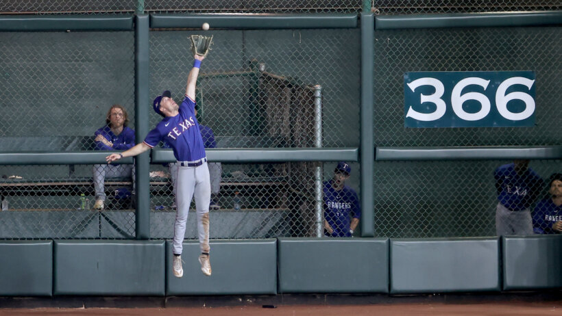 Texas Rangers outfielder Evan Carter making a catch at the wall