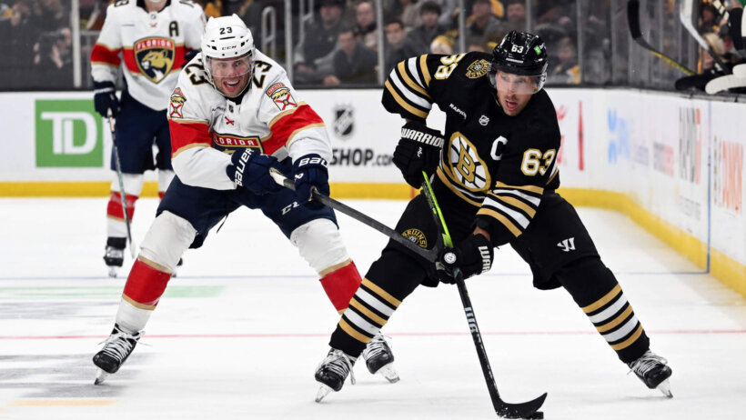 Boston Bruins left winger Brad Marchand skates with the puck while Florida Panthers center Carter Verhaeghe tries to stick-check him