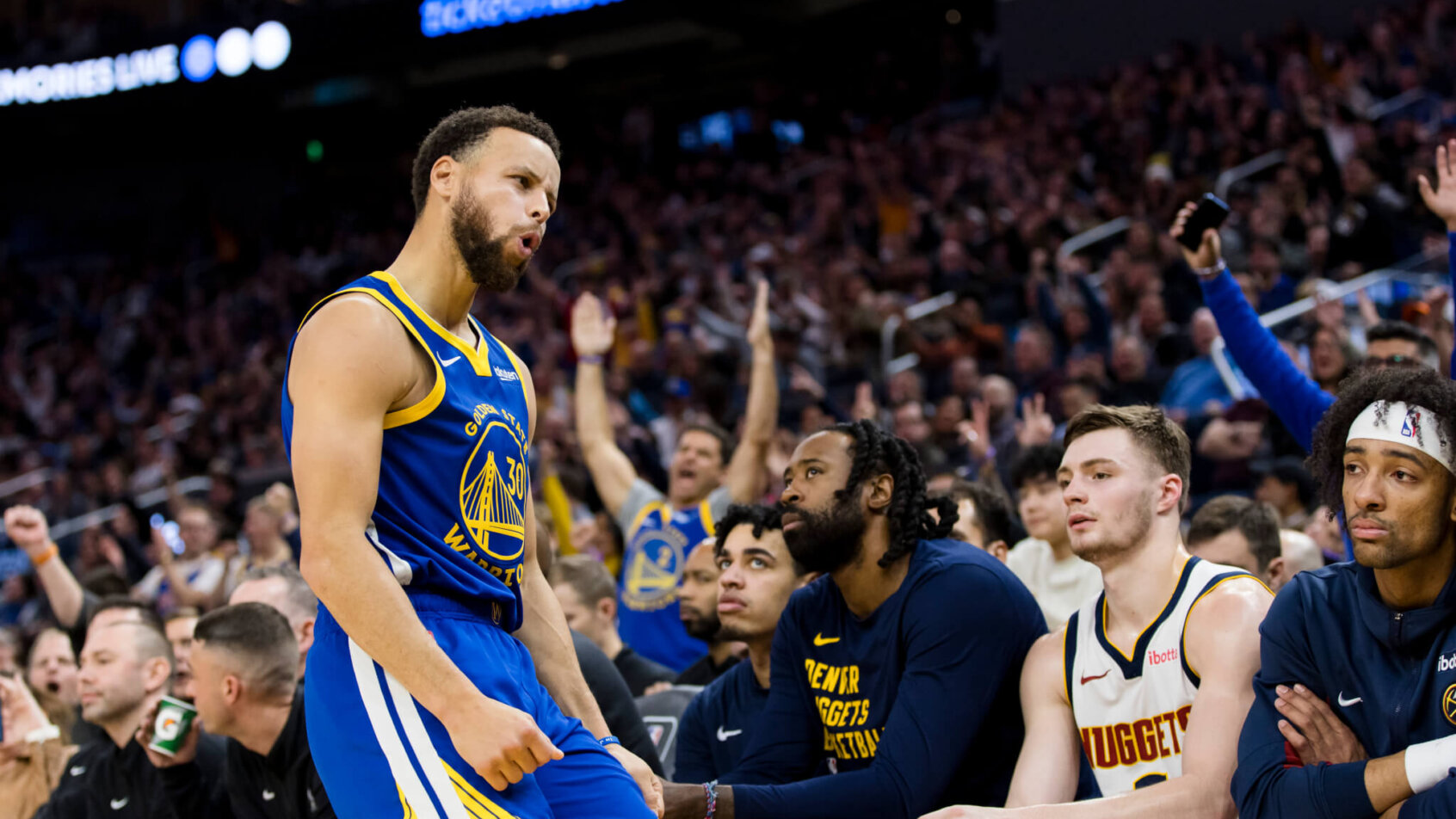 Golden State Warriors guard Stephen Curry poses in front of the Denver Nuggets bench