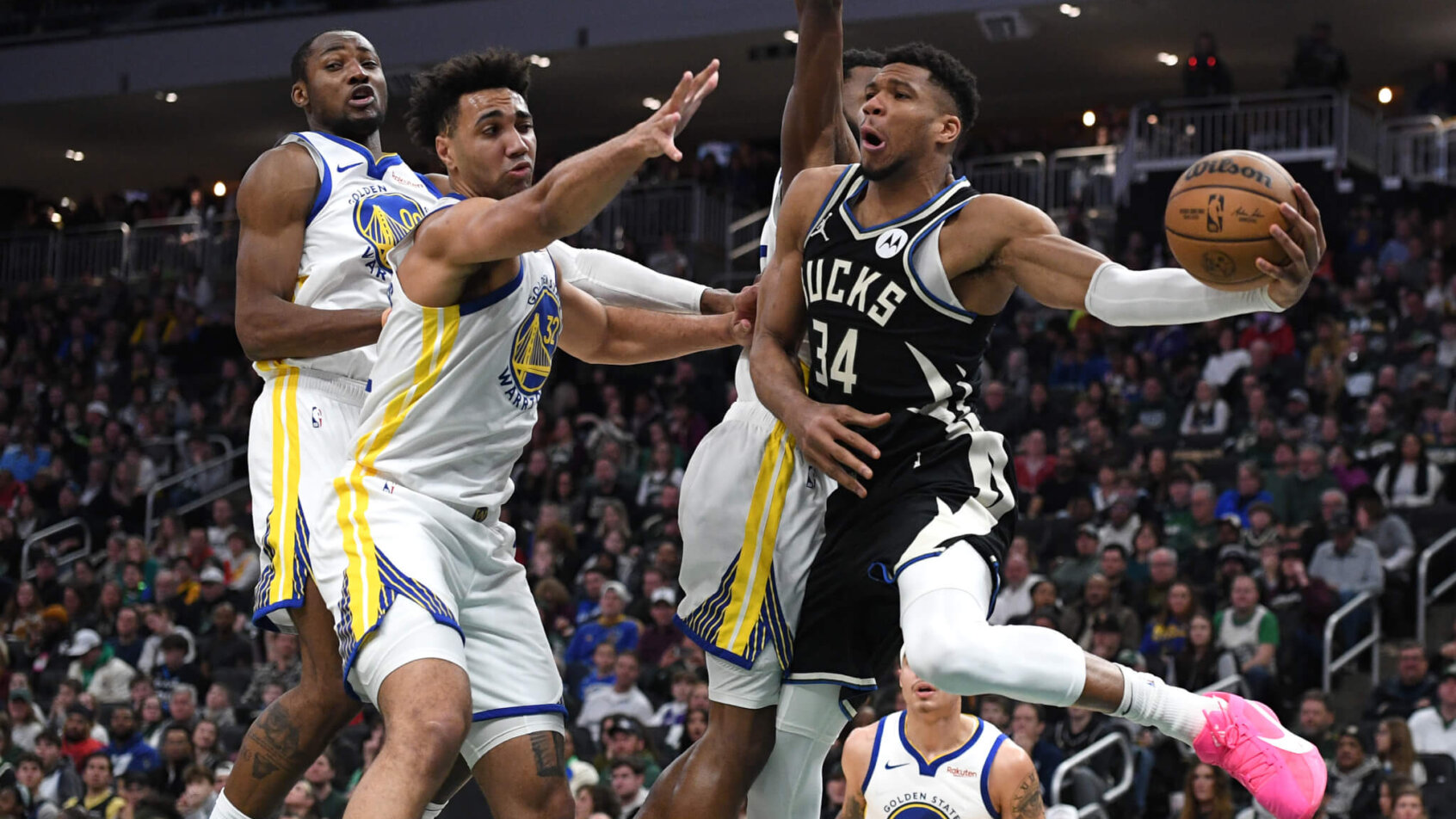 Milwaukee Bucks forward Giannis Antetokounmpo tries to pass around two Golden State Warriors