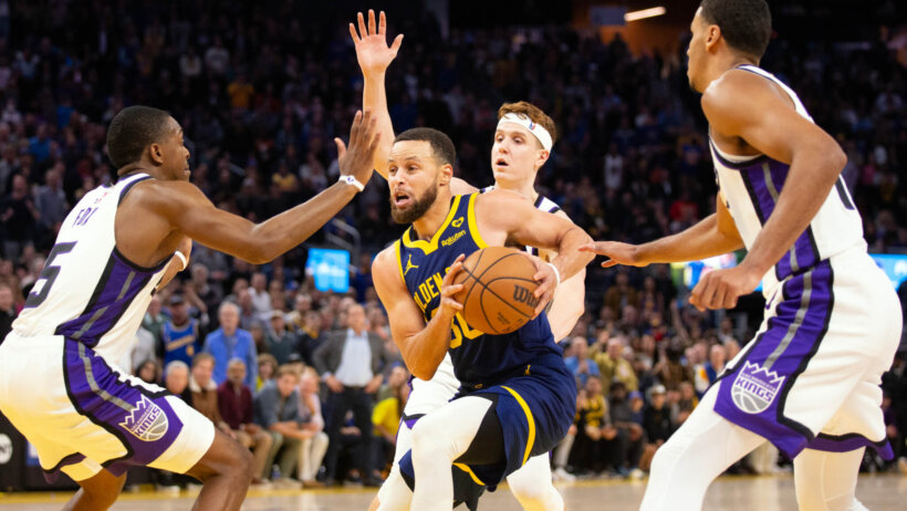Golden State Warriors guard Stephen Curry drives against three Sacramento Kings defenders