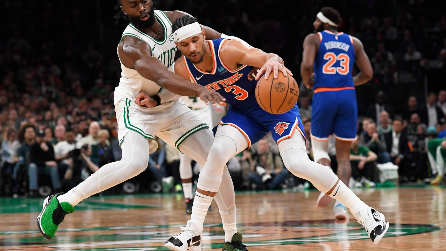 New York Knicks guard Josh Hart defends a basketball from Boston Celtics guard Jaylen Brown.