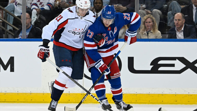 Washington Capitals center Aliaksei Protas and New York Rangers defenseman Adam Fox battle for the puck