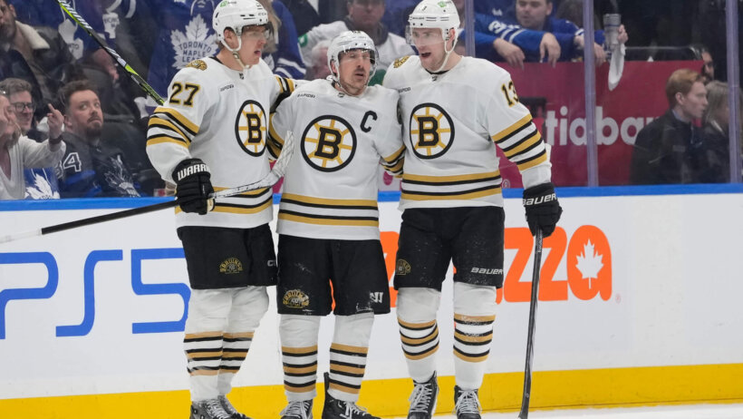Boston Bruins defenseman Hampus Lindholm and forward Charlie Coyle congratulate forward Brad Marchand