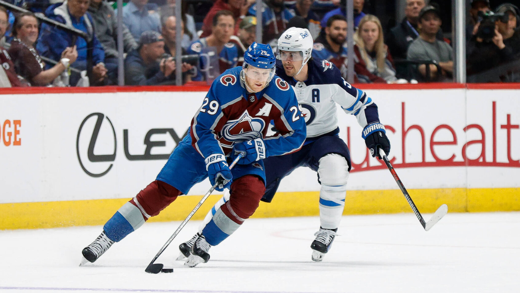 Colorado Avalanche center Nathan MacKinnon controls the puck ahead of Winnipeg Jets center Mark Scheifele