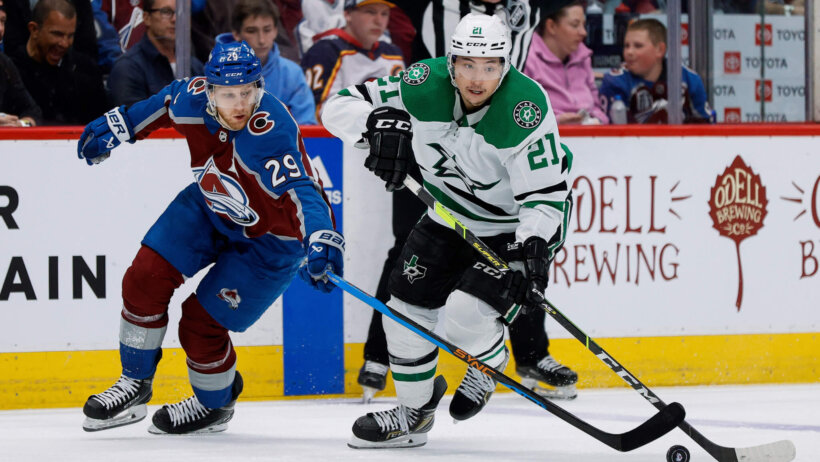 Colorado Avalanche center Nathan MacKinnon and Dallas Stars left wing Jason Robertson battle for the puck